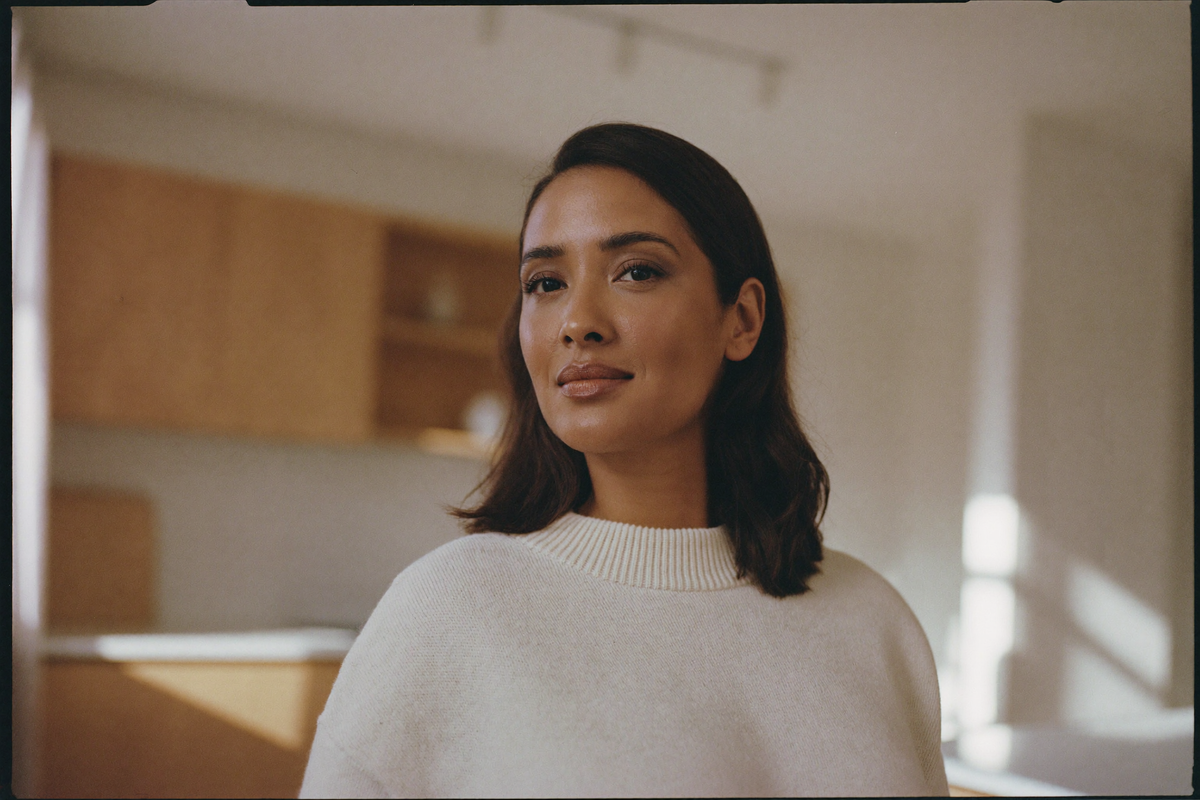A woman in her forties standing in a sunlit kitchen